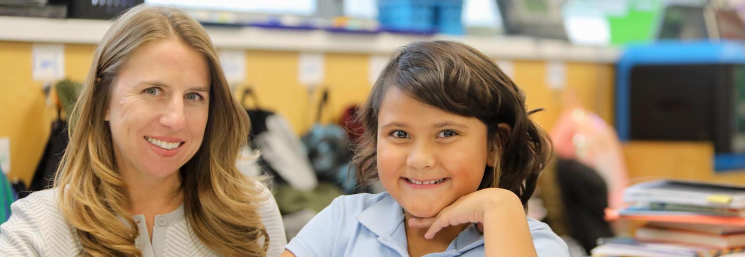 Principal posing with a student in class